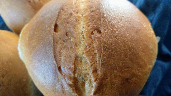 Knusprige Br&ouml;tchen aus Dinkelmehl liegen auf einem blauen Tuch und sind frisch aus dem Ofen.