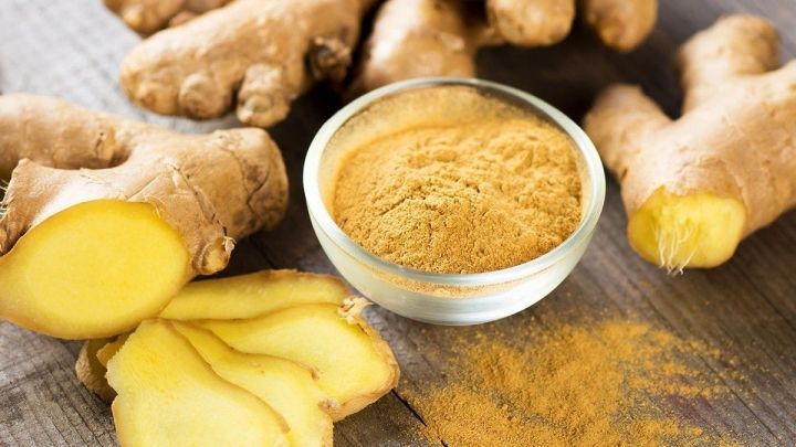 Frische Ingwerknollen und Ingwerpulver liegen auf einem Holzbrett und zeigen die gesundheitlichen Vorteile der Superknolle.