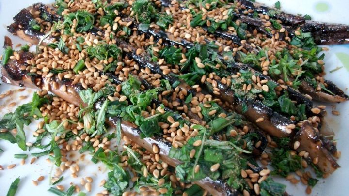 Gebackene Teriyaki-Auberginen liegen auf einem Teller, garniert mit Sesam und frischem Gr&uuml;n in einem hellen Raum.