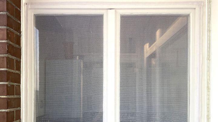 Ein flexibles Fliegengitter wird an einem wei&szlig;en Fenster montiert, um Insekten drau&szlig;en zu halten. Das Fenster ist in ein modernes Wohnumfeld integriert.