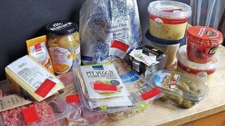 Lebensmittel mit Preisreduzierungen liegen auf einem Tisch, w&auml;hrend man f&uuml;r sparsames Einkaufen plant.