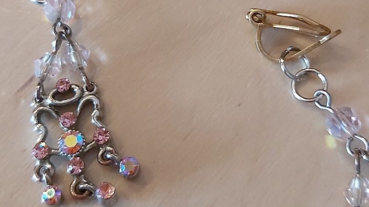 Bunte Kinderohrringe liegen auf einem hellen Holzuntergrund, bereit zum Basteln und Verzieren, mit glitzernden Kristallen.