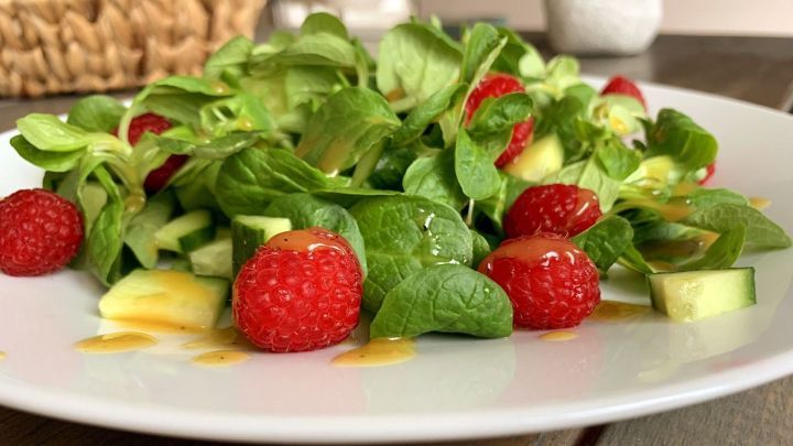 Ein frischer Feldsalat mit Himbeeren und Gurkenst&uuml;cken wird mit einem Honig-Senf-Dressing angerichtet.