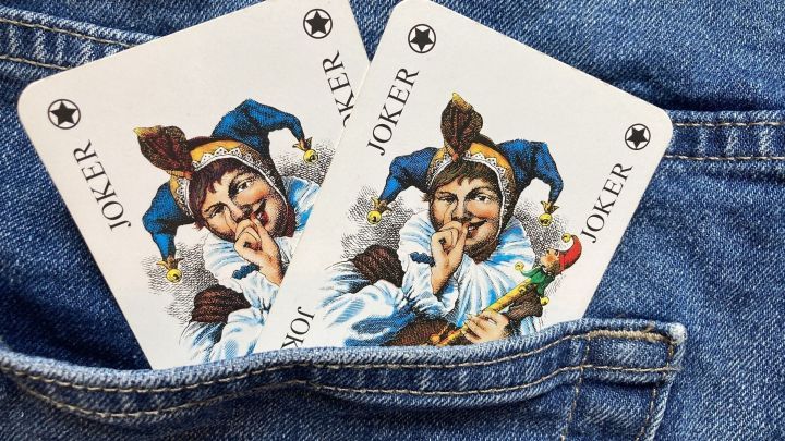 Zwei Joker-Karten stecken in der Tasche einer Jeansjacke, geheimnisvoll mit einem aufgeschlossenen Gesichtsausdruck und verspielt.