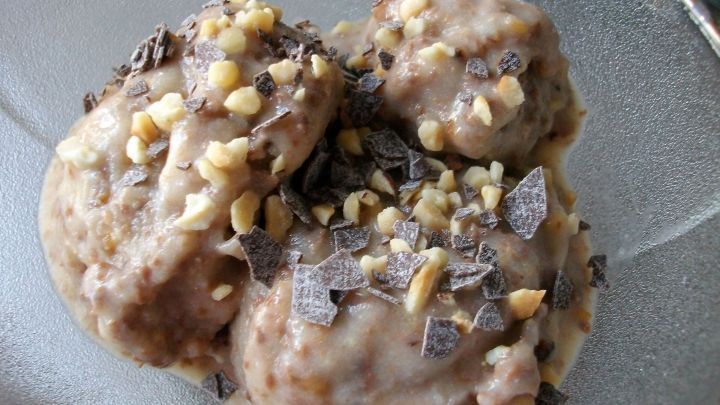 Bananeneis in einer Sch&uuml;ssel, garniert mit Schokoladenst&uuml;ckchen und Haselnusskernen, frisch zubereitet und cremig.