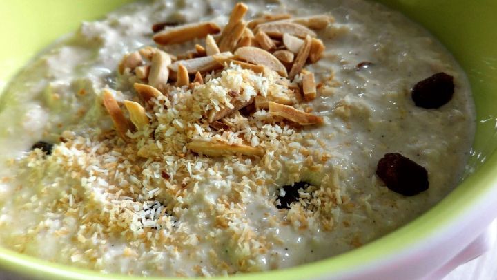 Eine Sch&uuml;ssel Bircher M&uuml;sli steht auf einem Tisch, belegt mit N&uuml;ssen und Kokosraspeln, ideal f&uuml;r ein gesundes Fr&uuml;hst&uuml;ck.