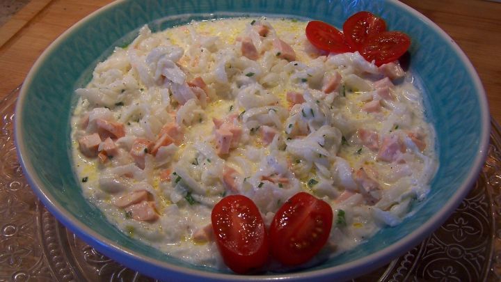 Ein frischer Rettichsalat mit Wiener W&uuml;rstchen wird in einer blauen Sch&uuml;ssel serviert, garniert mit Kirschtomaten.