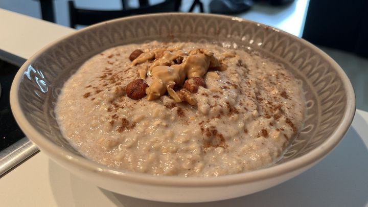 Ein Bananen-Porridge liegt in einem h&uuml;bschen Sch&uuml;ssel, garniert mit N&uuml;ssen und Erdnussbutter, im modernen K&uuml;chenumfeld.