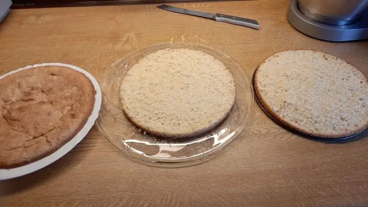 Mit einem großen Küchenmesser teile ich den Biskuit vorsichtig in drei Teile und entferne das Backpapier vom Boden.