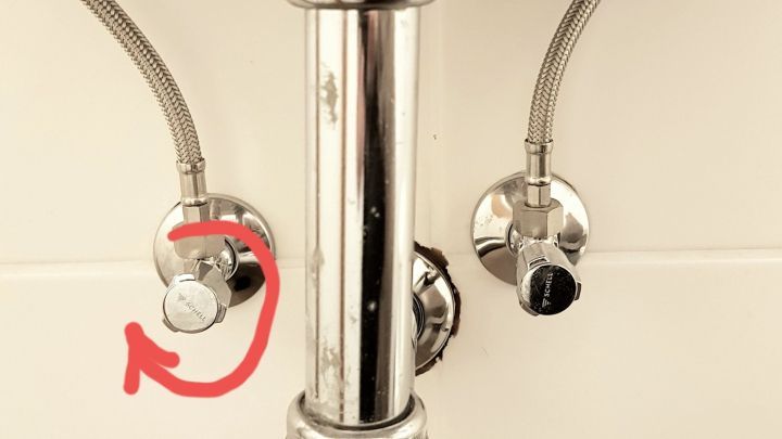 Ein Wasserhahn mit verchromtem Rohr wird abgedreht, um Warmwasser im Sommer zu sparen, in einem Badezimmer.