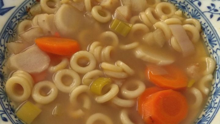 Eine Sch&uuml;ssel mit buntem Nudelgem&uuml;se in Br&uuml;he steht auf einem Tisch, bereit zum Essen und richtig aufbewahren.