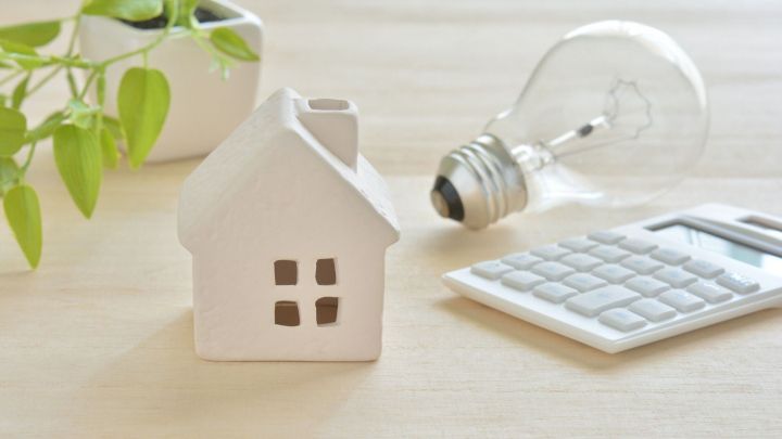 Ein stilisiertes Hausmodell steht neben einer Gl&uuml;hbirne und einem Taschenrechner, um Energiespartipps zu verdeutlichen.