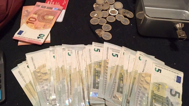 Staples of cash, including various Euro bills and coins, are neatly arranged on a surface next to a small lockbox.
