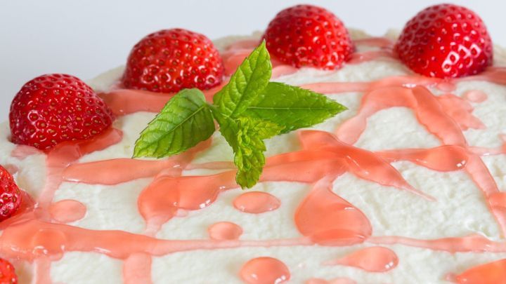 Ein cremiger No-Bake Spaghettieis-Kuchen ist dekoriert mit frischen Erdbeeren und einem Minzblatt.
