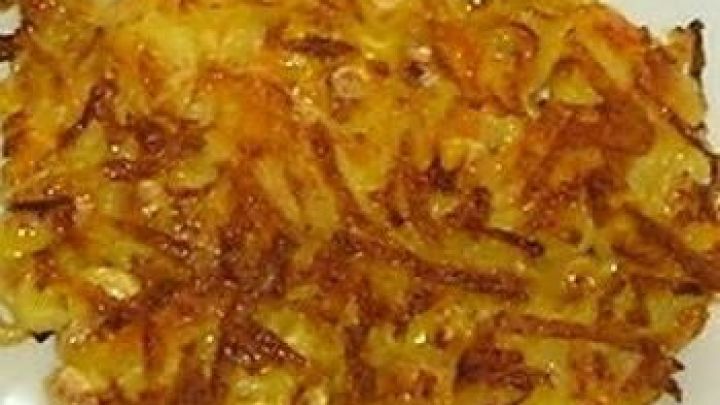 Ein knuspriger Gem&uuml;sepuffer, goldbraun gebraten, liegt auf einem wei&szlig;en Teller und zeigt eine feine Struktur aus geraspeltem Gem&uuml;se.