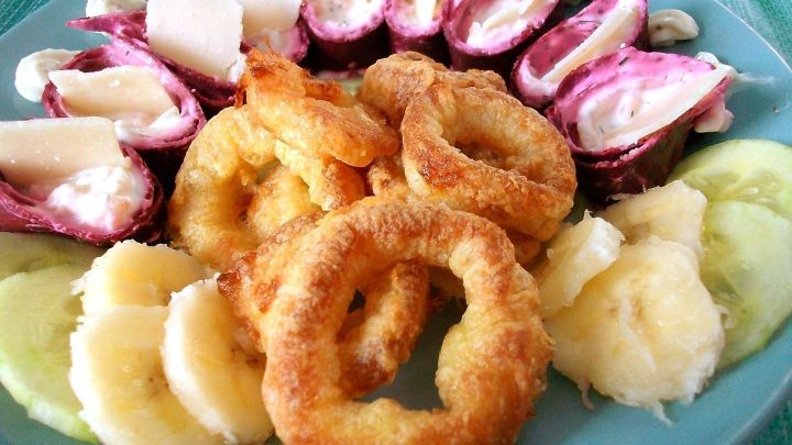 Rote Beete Tortillas zeigen bunte, gef&uuml;llte Rollen zusammen mit knusprigen Ringen und frischen Fr&uuml;chten auf einem Teller.