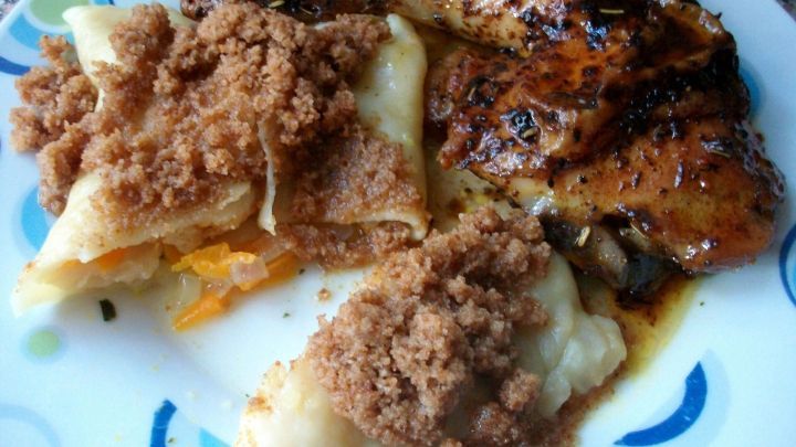 Saftiges Backofen-H&auml;hnchen liegt neben gef&uuml;llten Gem&uuml;seteigtaschen, die mit einer knusprigen Krume bestreut sind.