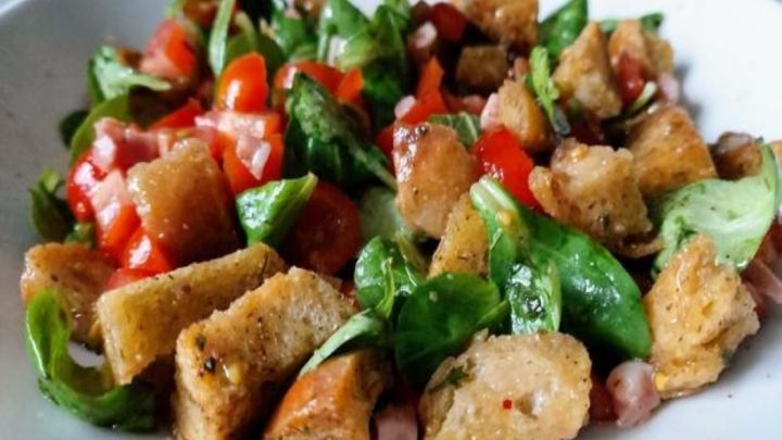Feldsalat mit Cro&ucirc;tons wird farbenfroh serviert, mit knackigem Gem&uuml;se und goldenen Brotw&uuml;rfeln in einer flachen Schale.