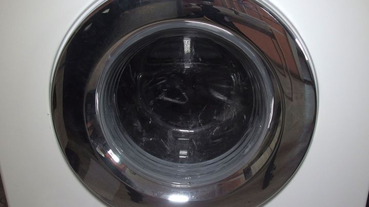 Die Waschmaschine &ouml;ffnet die T&uuml;r, um W&auml;sche einzuladen, und steht vor einer wei&szlig;en Wand in einem modernen Raum.