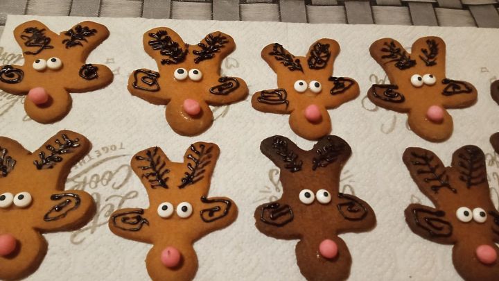 Pl&auml;tzchen in Rentierform sind dekoriert mit Augen und einer Nase, auf einem wei&szlig;en K&uuml;chenpapier pr&auml;sentiert.