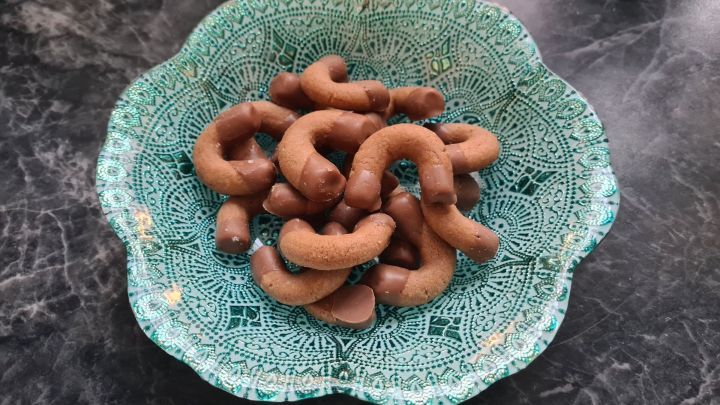 Kleine Nougatkipferl liegen in einer dekorativen, mintgr&uuml;nen Sch&uuml;ssel auf einem dunklen Tisch.