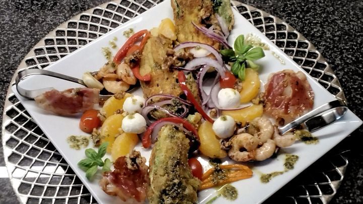 Panierter Romanasalat wird zusammen mit bunten Beilagen wie Garnelen, Tomaten und Zwiebeln auf einem eleganten Teller serviert.