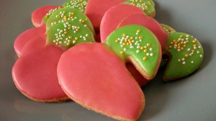 Bunte Dinkel-Tassenkekse mit pinker und gr&uuml;ner Zuckerglasur liegen auf einem grauen Teller und laden zum Naschen ein.