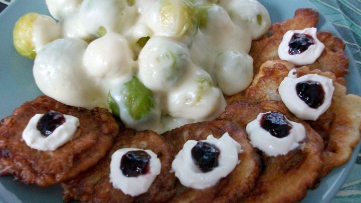 &Uuml;berbackene Rosenkohlh&auml;lften liegen neben knusprigen Birnenk&uuml;chlein, die mit Sahne und Marmelade garniert sind.