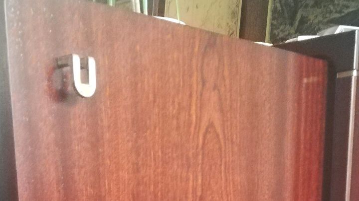 Ein mahagonifarbener Schrankt&uuml;r-Teil zeigt eine polierte Oberfl&auml;che, in einem Wohnraum mit dunklem M&ouml;bel umgeben.