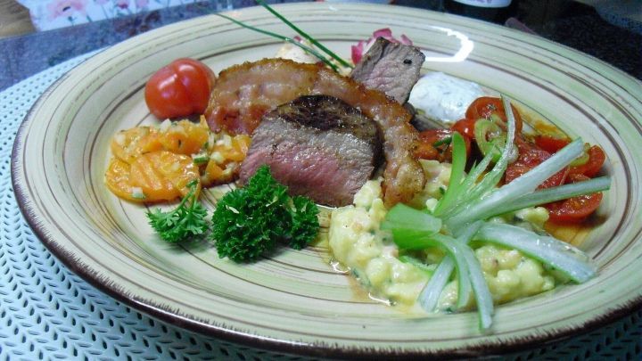 Bunter Salatteller mit Wildschweinsteak pr&auml;sentiert saftiges Steak, begleitet von Gem&uuml;se und frischen Kr&auml;utern auf einem Teller.