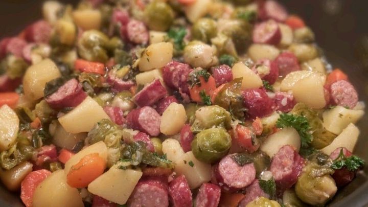 Bunte Gem&uuml;seeintopf mit M&ouml;hren, Kartoffeln und Mettw&uuml;rstchen kocht in einem Topf und bietet eine herzhafte Mahlzeit.