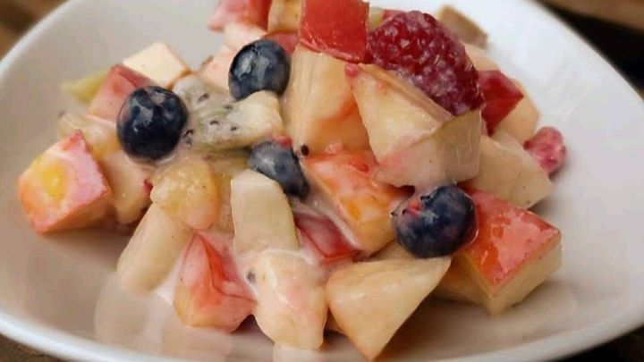 Ein bunter Obstsalat aus &Auml;pfeln, Blaubeeren und Himbeeren liegt in einer wei&szlig;en Schale und wirkt frisch und appetitlich.
