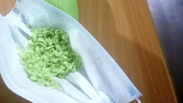 Ein Dufts&auml;ckchen aus einer Maskenform wird mit gr&uuml;nen, duftenden Schalen gef&uuml;llt und liegt auf einem Holzuntergrund.