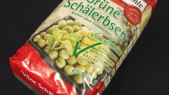 Gr&uuml;ne Erbsen in einer roten Verpackung liegen auf einem schwarzen Hintergrund, gekennzeichnet als gesund und ohne Salz.
