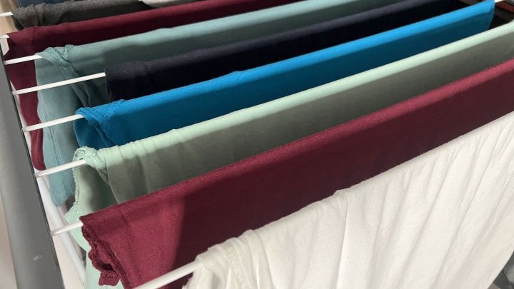 Bunte T-Shirts h&auml;ngen in einem W&auml;schegestell, frisch gewaschen und zum Trocknen bereit, um Deoflecken zu entfernen.