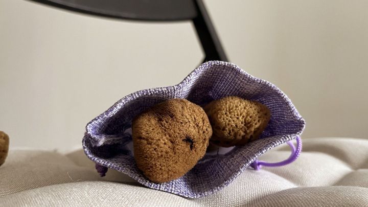 Ein Menstruationsschwamm liegt in einem lila Beutel auf einer hellen Oberfl&auml;che, bereit zur Verwendung, plastikfrei und nachhaltig.