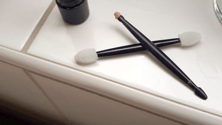 Ein fast leerer Lippenstift und zwei Applikatoren liegen auf einer hellen Oberfl&auml;che neben einem Heizk&ouml;rper.