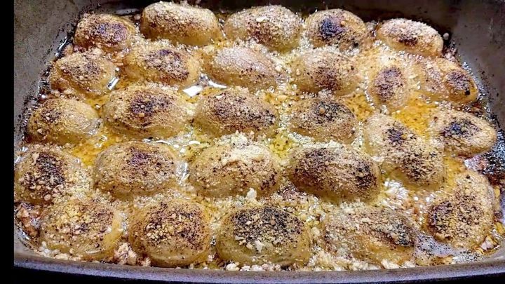 Kartoffeln, knusprig und goldbraun, &uuml;berbacken mit Parmesan, liegen in einer Auflaufform in hei&szlig;em, schaumigem &Ouml;l.