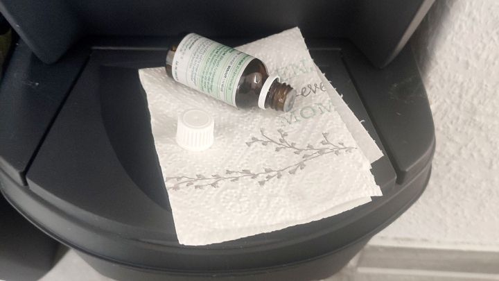 Ein braunes Fl&auml;schchen liegt auf einem St&uuml;ck K&uuml;chenpapier in einem M&uuml;lleimer, umgeben von einem hellen Boden und einer Wand.