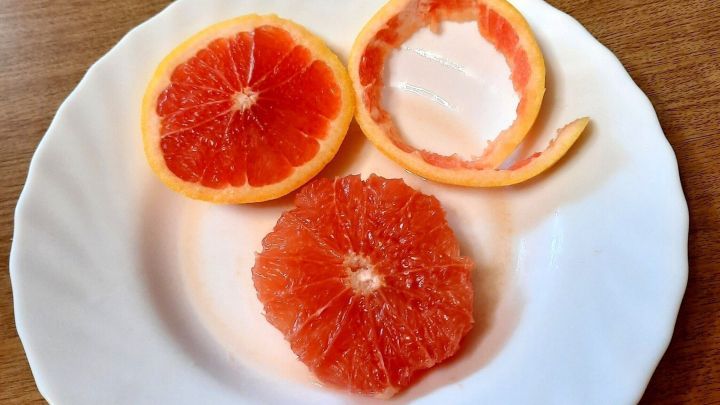 Halbe Grapefruits liegen auf wei&szlig;en Tellern, w&auml;hrend die Frucht sch&auml;len und vorbereiten wird, um genossen zu werden.