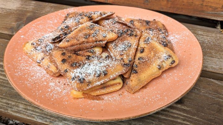 Leckere Muffins aus dem Sandwichmaker liegen auf einem Teller, bestreut mit Puderzucker und Schokoladenst&uuml;ckchen.