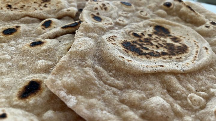 Flache, braune Sauerteigwraps liegen &uuml;bereinander, leicht angebr&auml;unt und frisch zubereitet in einer hellen K&uuml;che.