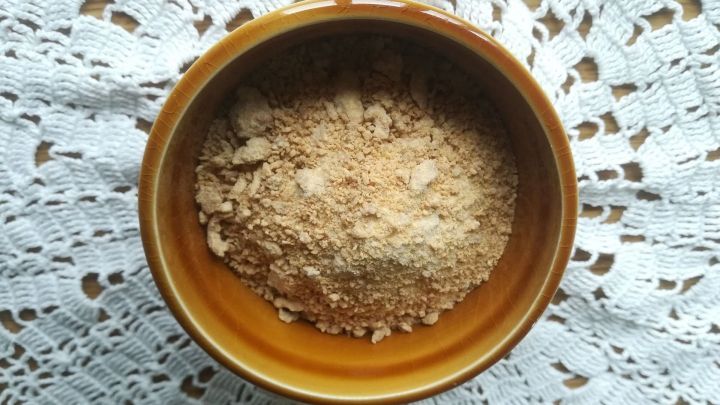 Eine braune Sch&uuml;ssel mit feinem, hellbraunem Pulver steht auf einer geh&auml;kelten Tischdecke, um Reste sinnvoll zu nutzen.