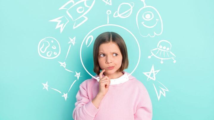 Ein M&auml;dchen denkt nach, umgeben von kreidigen Zeichnungen von Weltraumobjekten wie Raketen und Planeten auf einer t&uuml;rkisfarbigen Wand.