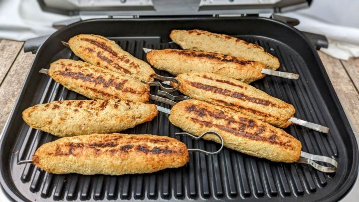 Auf dem Grill r&ouml;sten Frikandeln, w&auml;hrend sie gleichm&auml;&szlig;ig br&auml;unen und sich auf der Grillfl&auml;che befinden.
