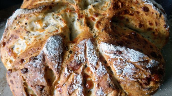 Ein frisch gebackenes Dinkelbrot mit Parmesan liegt auf einem Hintergrund, leicht mehlbest&auml;ubt und knusprig.
