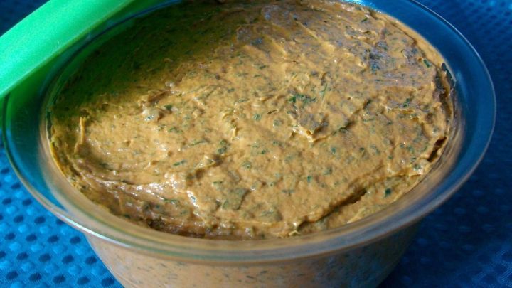 Eine cremige Tomatenbutter steht in einem durchsichtigen Beh&auml;lter auf einem blauen Untergrund und wartet auf Verwendung.