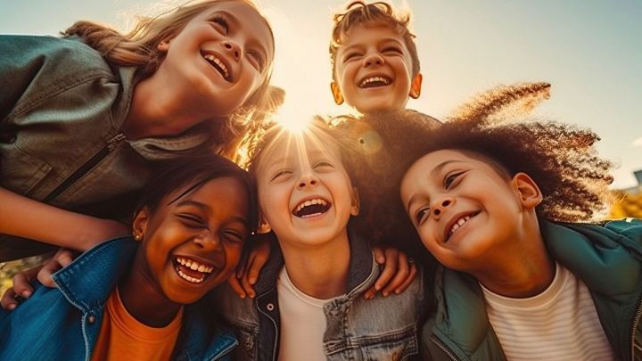 Sechs lachende Kinder stehen im Sonnenlicht und dr&uuml;cken Freude und Freundschaft in einer harmonischen Umgebung aus.