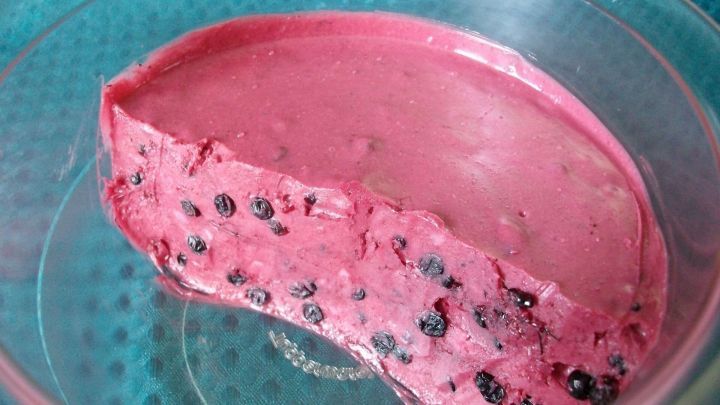 Eine cremige Holunderbutter mit einer leuchtend pinken Farbe, serviert in einer Schale auf einem strukturierten Hintergrund.