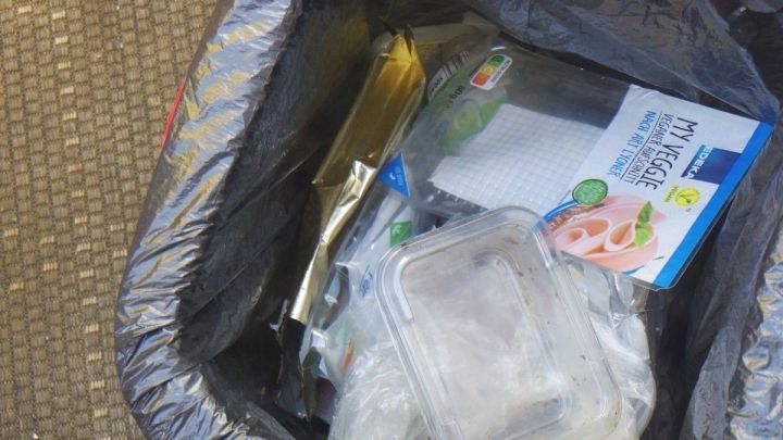 Eine schwarze M&uuml;llt&uuml;te enth&auml;lt unsortierten M&uuml;ll, darunter Verpackungen und Beh&auml;lter, die richtig getrennt werden sollten.